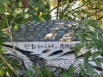 signatuur Nouch (juli 2024); steentjes op de muur horen bij de brug