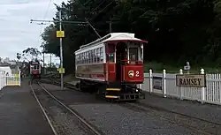 Vooraan instappen, alleen afgesloten met een hek. Achter is een open bijwagen.