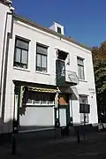 Hoekpand met gepleisterde lijstgevel. Gevel gewijzigd door het inbrengen van een winkeldeur en etalageruimte plm. 1900 en balkon boven de winkeldeur 20e eeuw. Woonhuisingang aan de Provoostraat