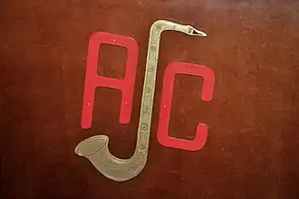 Een sculptuur gelijkend op het logo van de Antwerpse Jazzclub, bevestigd aan de voorkant van het vouwbare houten scherm dat de sprekerszone omrand tijdens de dinsdagavond-sessies van de jazzclub in haar clubhuis (13 September 2016).