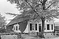 Gepleisterde hoeve met puntgevel en rieten zadeldak. Stal van gepotdekselde houten delen achter het woonhuis onder hetzelfde dak. Vensters met zes- en 20-ruitsschuiframen en luiken. In de geveltop een leeuwekopje als kraagsteen