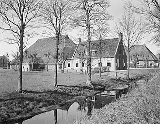 Kop-hals-rompboerderij met lang voorhuis met omlijste ingang met pilasters in de lange gevel