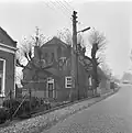Boerderij, evenwijdig aan de weg gebouwd, onder rieten wolfdak. In de voorgevel vlechtingen, vensters met kruiskozijnen en luiken