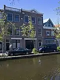 Bedrijfspand met bovenwoning, in 1916 in samenhang met het links belendende pand gebouwd in een traditionalistische stijl met toepassing van klassieke architectonische details.