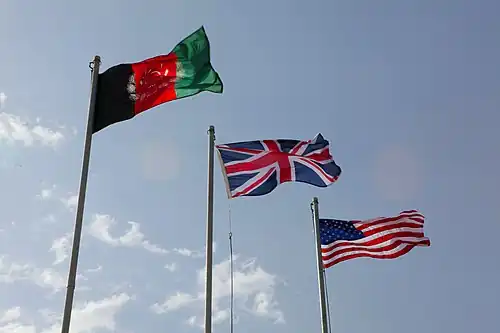 Afghaanse, Britse en Amerikaanse vlaggen op palen tijdens een ceremonie in de provincie Helmand (2010)
