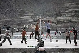 Afghaanse en Amerikaanse soldaten spelen een volleybalwedstrijd op buitenpostbasis Bostick in de provincie Kunar in juli 2009. Door samen te sporten bouwen ze een sterkere samenhang op.