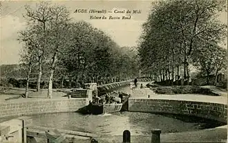 Ansichtkaart omstreeks 1900, zicht vanuit het westen. De sluis is nog rond, een schuit met vee vaart vanuit het Canal du Midi naar binnen.