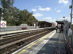 Sporen en perrons met de betonnen perronkappen ter hoogte van het stationsgebouw.