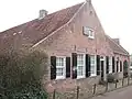 Gepleisterd laag huis, boerderij, luiken aan de ramen, brede topgevel