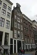 Huis uit 1720 met gevel, voorzien van de oorspronkelijke bedrijfspui en een rollagentop