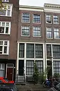 Huis met boven de hoge houten pui 19e-eeuwse gevel onder rechte lijst waarboven een dakvoorschot