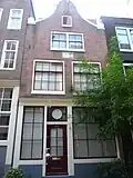 Bij de restauratie nagenoeg in de oude vorm herbouwd, in oorsprong uit de 17e eeuw daterend huis met latere gevel onder eenvoudige klokvormige top.
