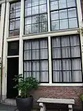 Huis met gevel onder rechte klossenlijst waarboven een bakstenen topje