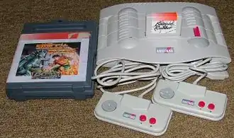 Een Amstrad Gx4000-spelcomputer met controllers en spelcartridge