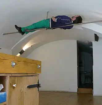 Pielage tijdens een performance, liggend op een trekstang in een Utrechtse werfkelder (2015)