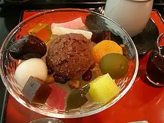 Anmitsu met in het midden een bolletje anko (zoete rodebonenpasta) en daaromheen kanten-blokjes, fruit en mochi-balletjes.