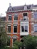 Herenhuis met beneden- en bovenwoning en hek, gebouwd in overgangsarchitectuur met invloeden van de art nouveau in detaillering en materiaalgebruik