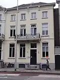 Huis met gepleisterde lijstgevel met consoles onder de kroonlijst en balkon met mooi gietijzeren hek