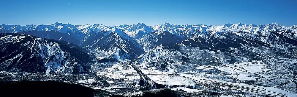 Luchtfoto van de vier skigebieden. Van links naar rechts: Aspen Mountain (boven het stadje Aspen), Aspen Highlands, Buttermilk en Snowmass.