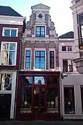 De Rozijnenkorf. Huis met rijk van beeldhouwwerk voorziene halsgevel. Winkelpui uit 1900. Na een grote brand in 2002 geheel gerenoveerd