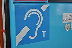 Japan - Een duidelijk zichtbaar bord in een bus geeft aan dat er een ringleiding (audio-inductiesysteem) aanwezig is voor mensen met een gehoorapparaat. Dit systeem zorgt ervoor dat reizigers met gehoorverlies spraak beter kunnen verstaan, bijvoorbeeld bij omroepberichten.