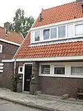 Blok met 8 keukenwoningen, zo genoemd vanwege destijds nieuwe plaatsing van keuken aan de voorzijde, aan de zijkant een houten topgevel, bouwstijl Amsterdamse School, samen met de poortgebouw langs de Purmerweg centraal deel van Tuindorp Nieuwendam