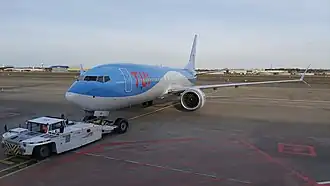 Een pushback truck van Aviapartner gekoppeld aan een Boeing 737