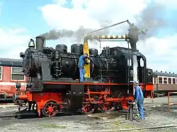 Een stoomloc die voorzien wordt van water bij de stelplaats van Mariembourg.