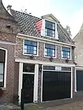 Huis met dwars zadeldak. Oorspronkelijk deur en bovenramen