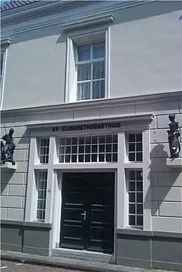 Ingang van het Sint-Elisabethsgasthuis aan de Bagijnenstraat met aan weerszijden een beeld van Margriet Barends. Ze tonen St. Elisabeth &nbsp;en St. Juriën (St. Joris). De laatste verwijst naar het Sint-Jurriëngasthuis dat hier gelegen was.