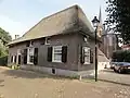 Boerderij op de hoek van de kerkstraat, bestaande uit een woongedeelte, evenwijdig aan de kruisstraat en een loodrecht daarop gebouwde stal