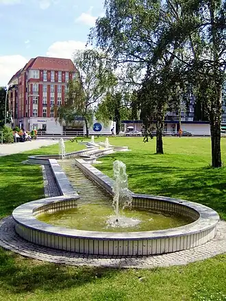 Groenvoorziening met fontein op het plein, met op de achtergrond het metrostation