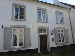 Voormalig kanunnikenhuis met zadeldak evenwijdig met de straat met haakse achtervleugel en rechts een vooruitspringend gedeelte eveneens met zadeldak evenwijdig met de straat