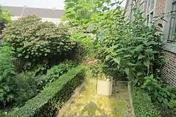 Ommuurd voorhofje met beplanting aan huizen grenzend aan Badderijstraat