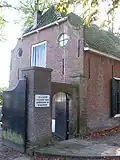 Boerderijtje, laag gebouw met topgevels, kleine roeden ramen met luiken.