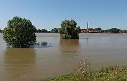 Hoog water in de Waal met steenfabriek op achtergrond