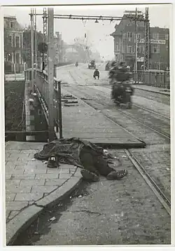 Twee Canadese soldaten op een motor kijken naar het lijk van een Duitse soldaat voor de Herebrug