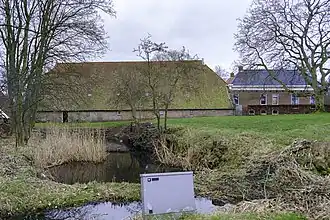 Boerderij met woonhuis onder pannen schilddak, schuur onder afgewolfd rieten zadeldak en bijschuur