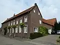 Hoeve van baksteen om een gesloten binnenplaats. Het woonhuis heeft lateiboogomlijstingen van Naamse steen en ankers. Deur en snijraam in late Lodewijk XVI-stijl