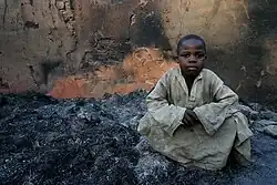 Jongen gezeten tussen verbrande overblijfselen