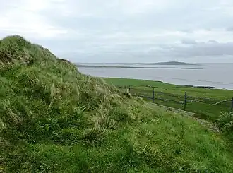 De Blackhammer Chambered Cairn met uitzicht over Eynhallow Sound.