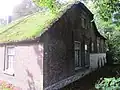 Boerderij waarvan het dwarse woongedeelte rechts een onderkelderde opkamer heeft en gedekt wordt door een rieten wolfdak
