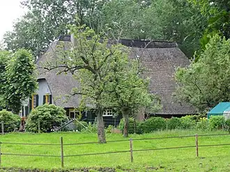 Mooi gelegen hoeve met rieten wolfdak en vensters met luiken en kleine roedenverdeling. Op het erf goede roedenbergen en wagenschuren
