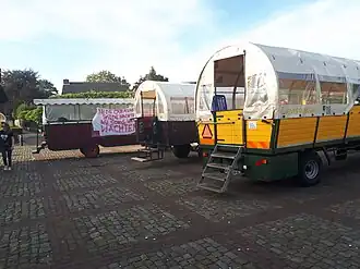 Een moderne boerenovertrek bestaande uit een aantal janpleziers geparkeerd voor een kroeg te Casteren.