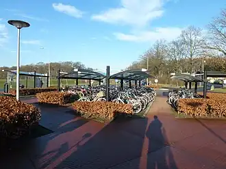 De fietsenstalling met daarachter de parkeerplaats en links perron B