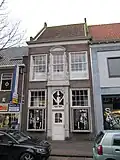 Pand met verdieping en dwars zadeldak. De lijstgevel heeft een rijk gebeeldhouwde middenas in vroege Lodewijk XV-stijl