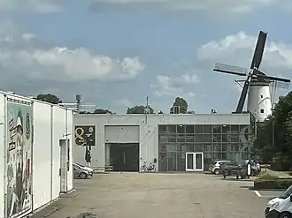 Zicht vanuit het kantoor van Brouwerij De Molen op het brouwhuis, met Molen De Arkduif op de achtergrond