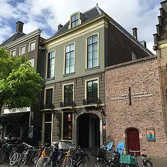 De galerijzaal bevindt zich op de 2e etage van het gebouw in het midden. De hoofdentree is toegankelijk via het poortje in de bakstenen muur rechts