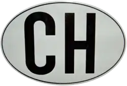 ovaalvormig wit veld waar van de breedte groter is dan de hoogte. In het veld staan twee zwarte hoofdletters: de C en de H