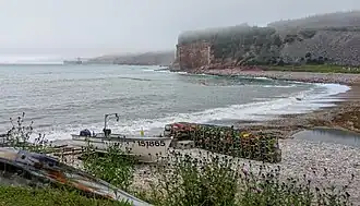Vissersbootje en -gerei op het keienstrand van Lower Cove